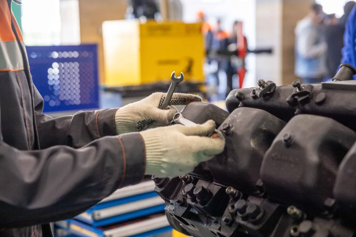 Hands using a wrench to maintain machinery in a workshop.