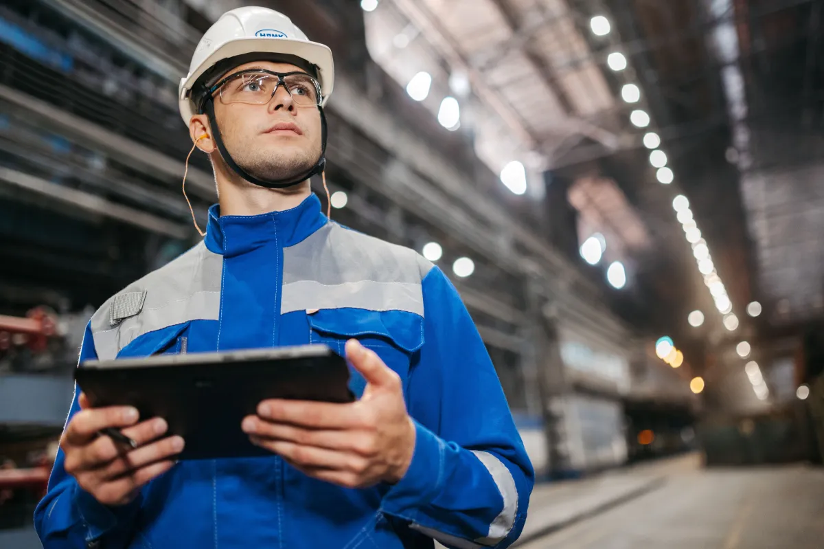 An industrial worker reviewing information on a tablet inside a factory.