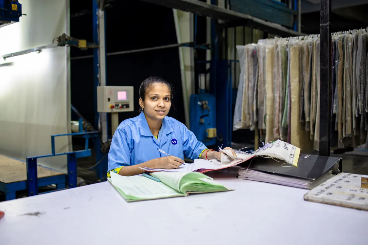 A factory worker reviewing paperwork at a workstation.
