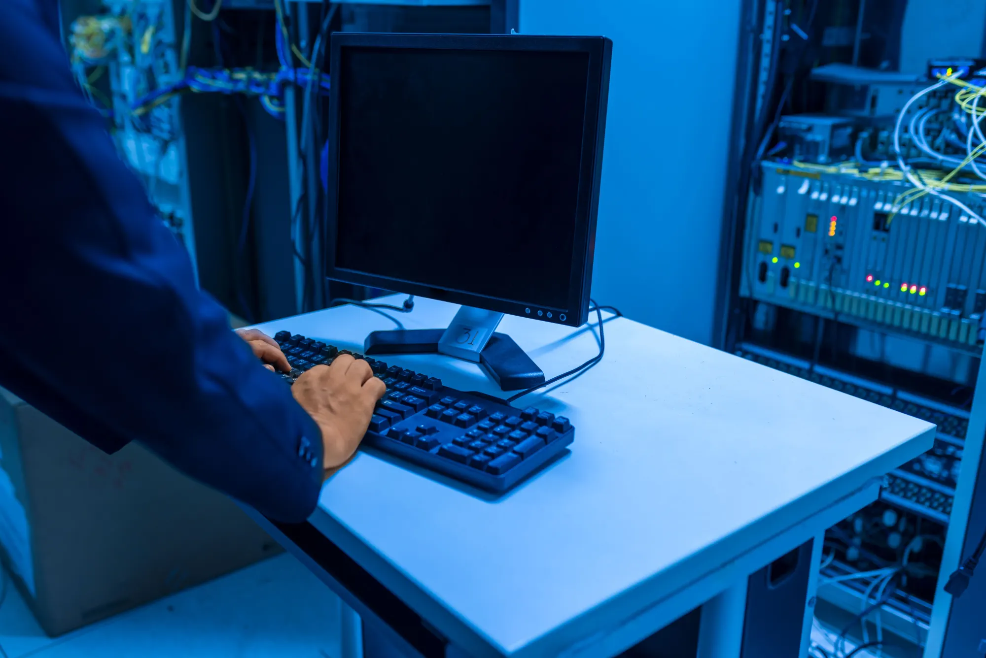 A technician working at a keyboard among server racks.
